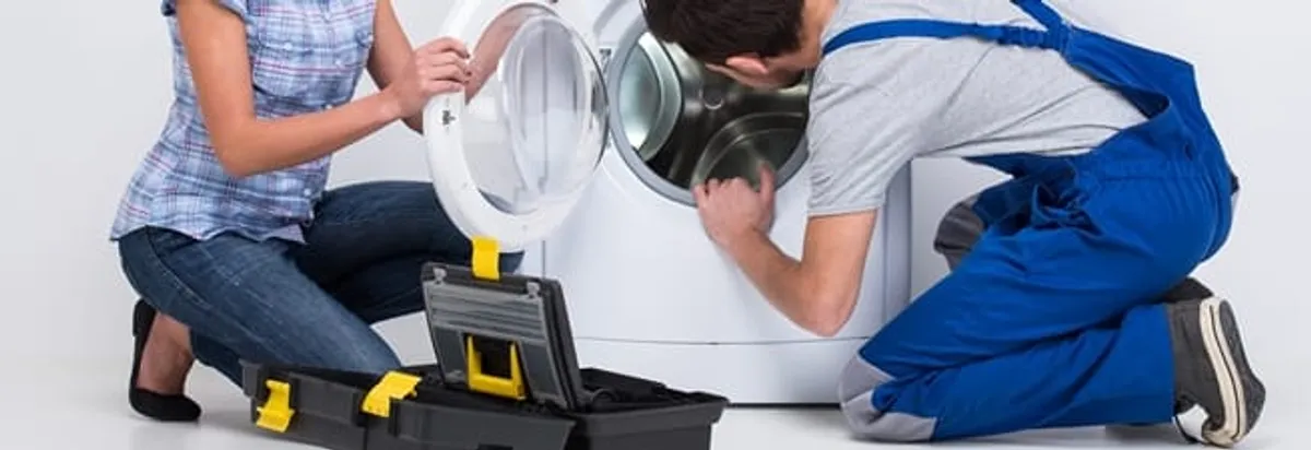 Washer repair technician inspecting a front-load washing machine with tools in Nashua, NH