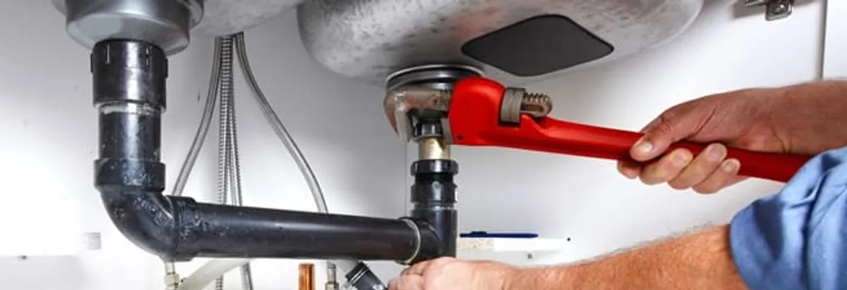 Garbage disposal repair technician tightening the sink drain and disposal connection in Nashua, NH