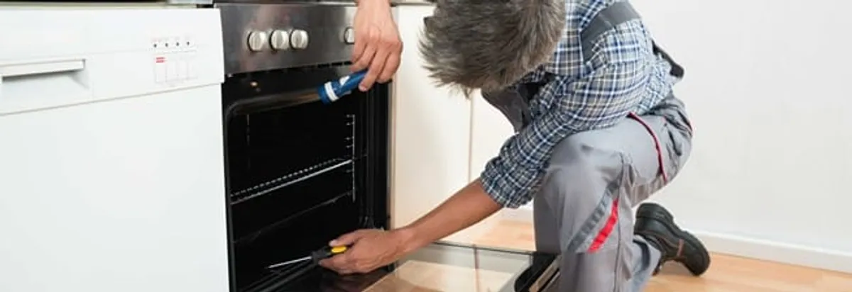 Oven repair technician inspecting and servicing an electric oven in Nashua, NH