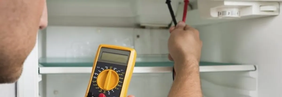 Refrigerator repair technician testing electrical components with a multimeter in Nashua, NH