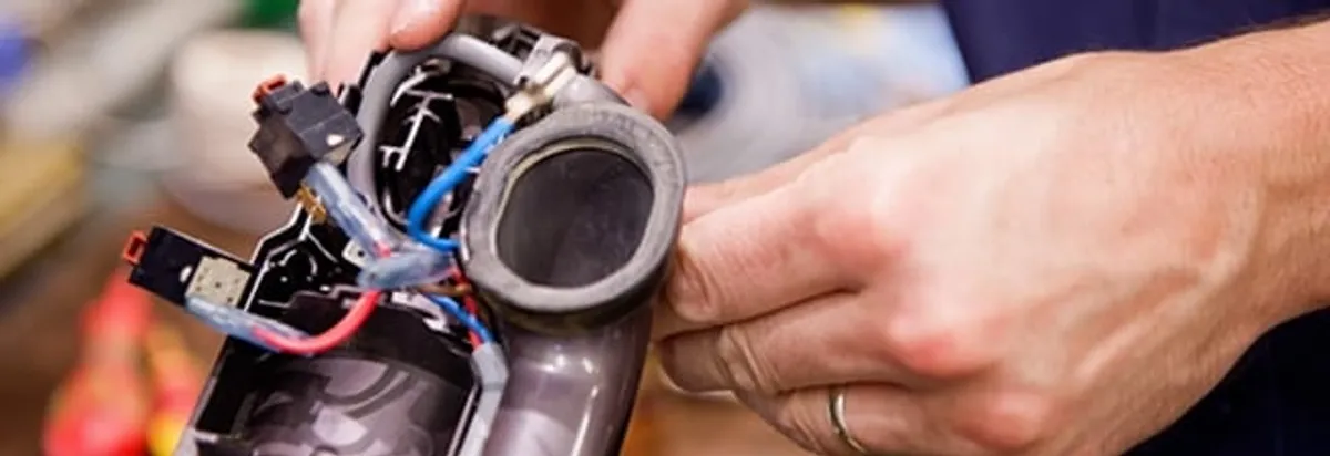 Vacuum repair technician reconnecting wiring and components in Nashua, NH
