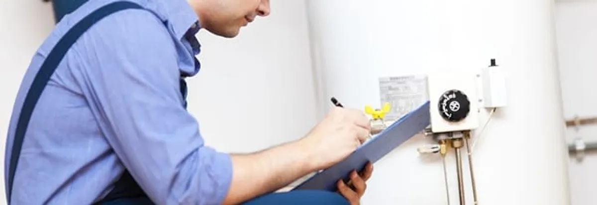 Water heater repair technician inspecting the unit and recording service notes in Nashua, NH