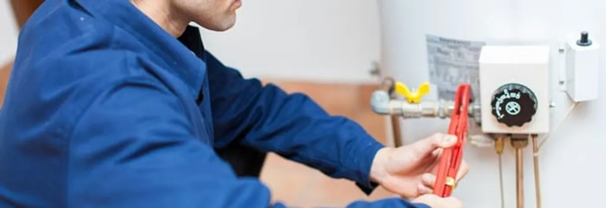 Water heater repair technician adjusting the temperature control and gas valve in Nashua, NH